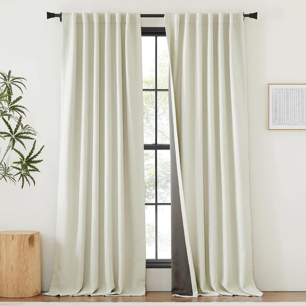 Cream linen blend curtains with dark blackout lining, elegantly pleated and hung on a black rod.