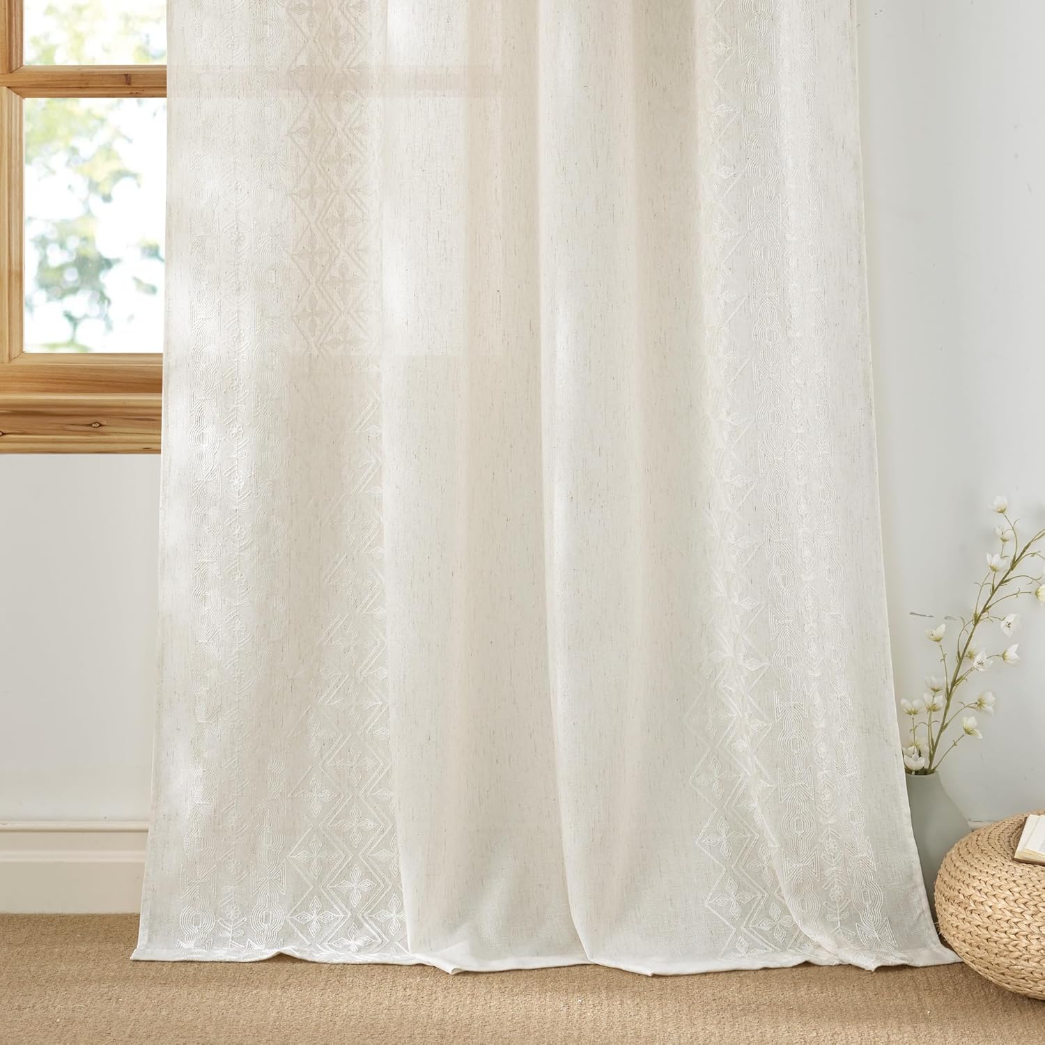 Cream linen semi-sheer curtain panel with intricate geometric embroidered patterns, filtering light.