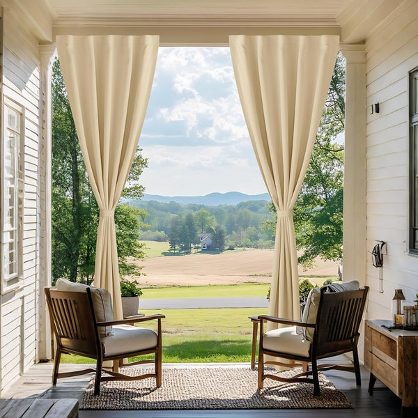 Cream tie-back outdoor curtains on a porch overlooking fields and trees.