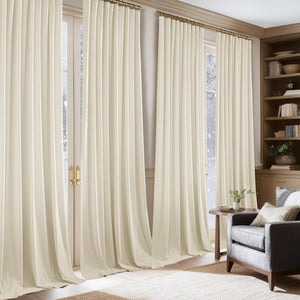 Cream pleated drapes hanging from a brass rod over tall glass doors in a cozy room.