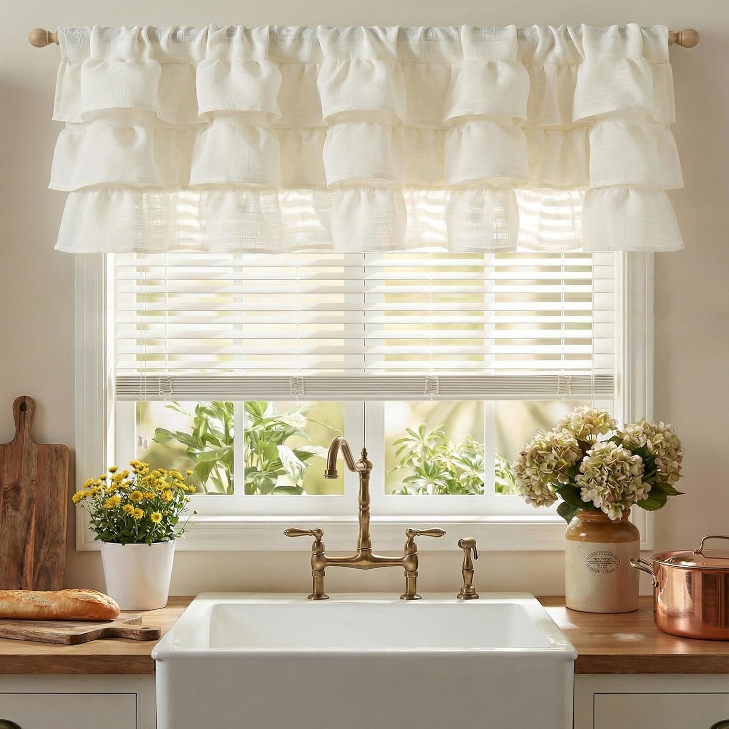 Cream linen tiered ruffle valance hanging over a kitchen window, offering a charming farmhouse look.