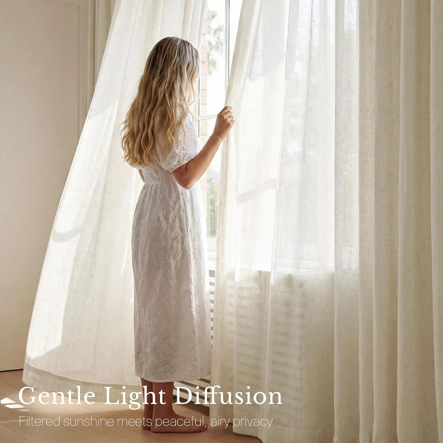 Woman by window holding light-diffusing cream sheer linen curtains in a bright, airy room