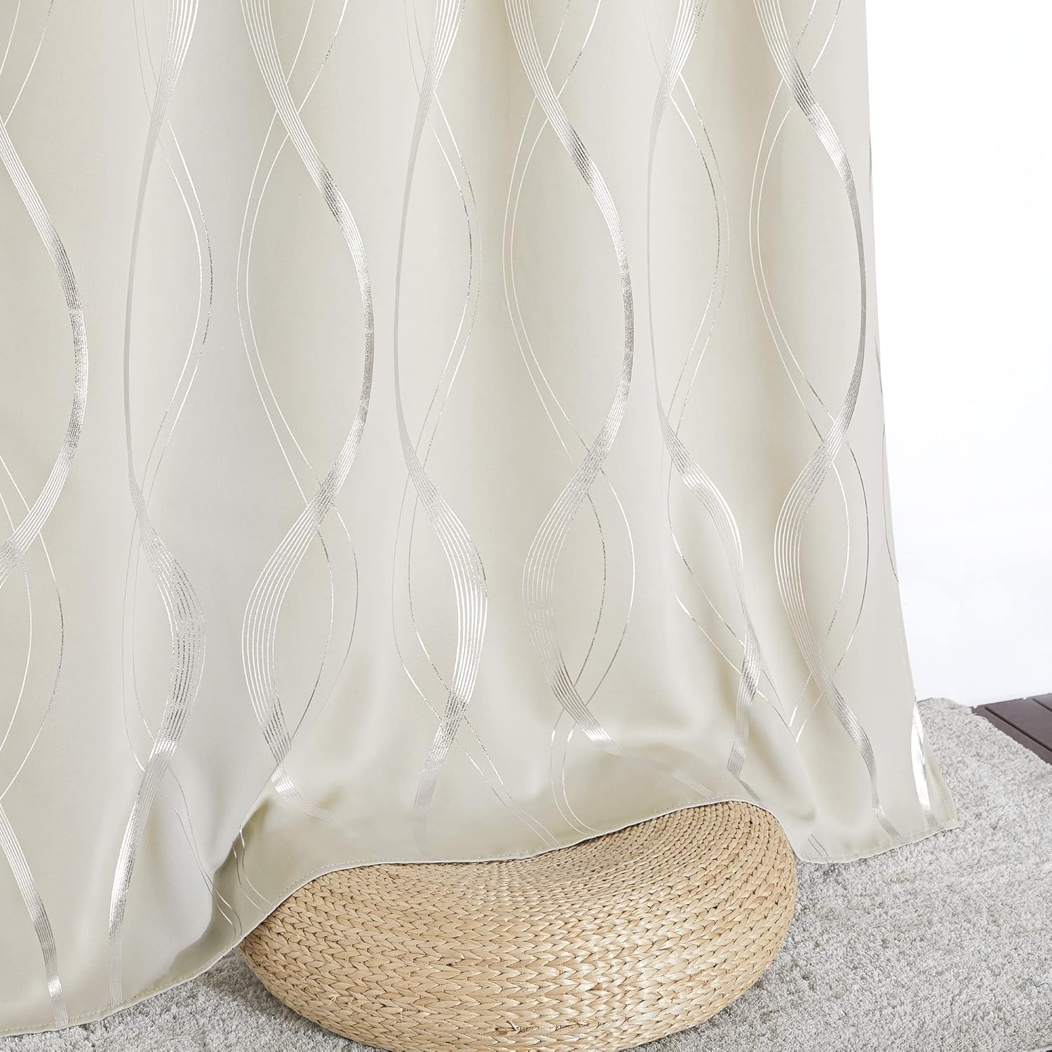 Cream blackout curtain featuring an elegant shimmering silver wavy pattern, draped over a woven ottoman.