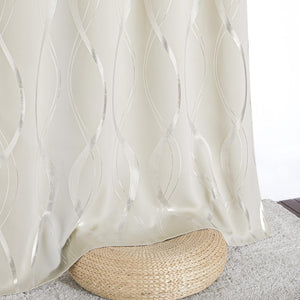 Cream blackout curtain featuring an elegant shimmering silver wavy pattern, draped over a woven ottoman.