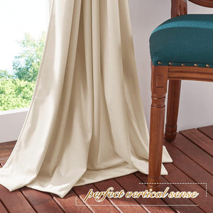 Cream smooth window drapes with good drape, pooling on dark wood floor. Outdoor greenery visible.
