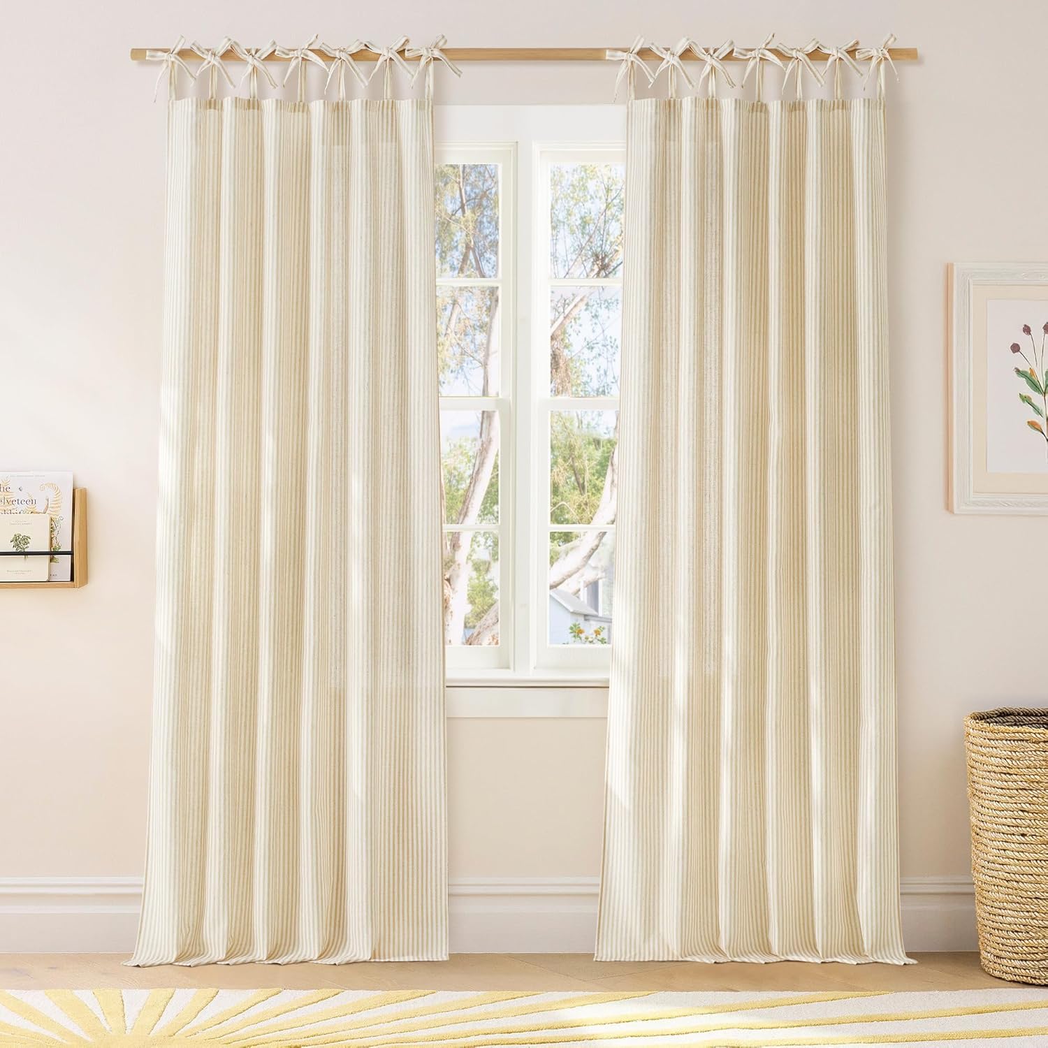 Cream pinstriped tie-top curtains crafted from natural fabric, elegantly hung on a wooden rod in a bright room.