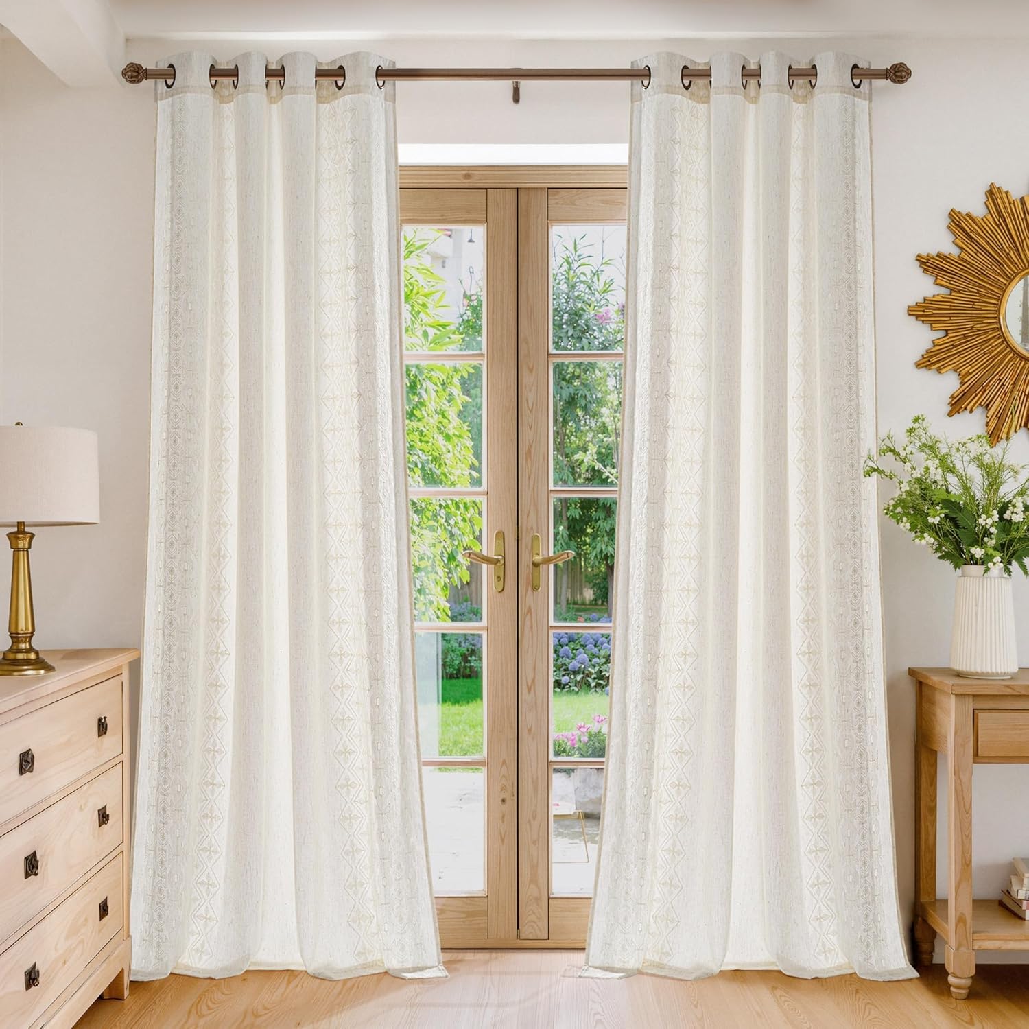 Light cream curtains with a subtle geometric border and grommet top style, hung in a bright living space.