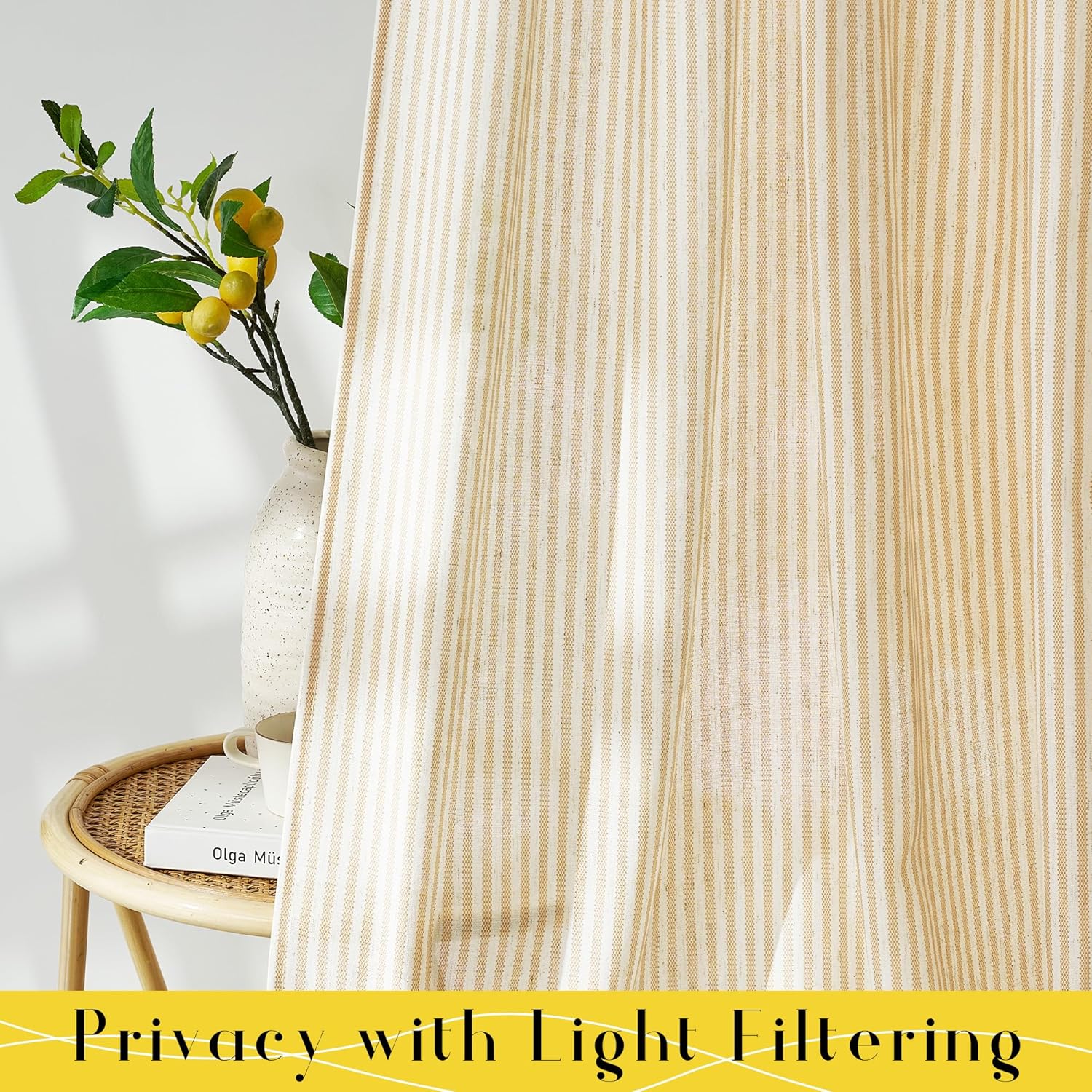 Cream and tan vertical striped light filtering curtain hangs beside a rattan side table with a lemon branch.
