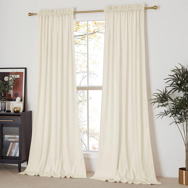 Elegant cream velvet rod pocket curtains hanging on a brass rod over a bright window, pooling on the floor.