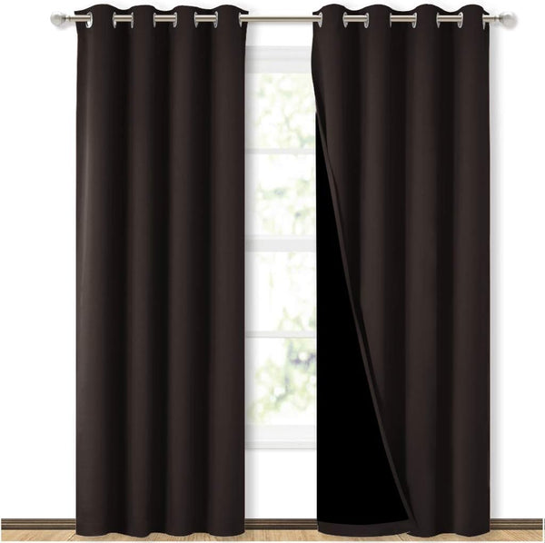 Dark brown blackout curtains with silver grommet tops, one panel pulled back showing the dark lining.