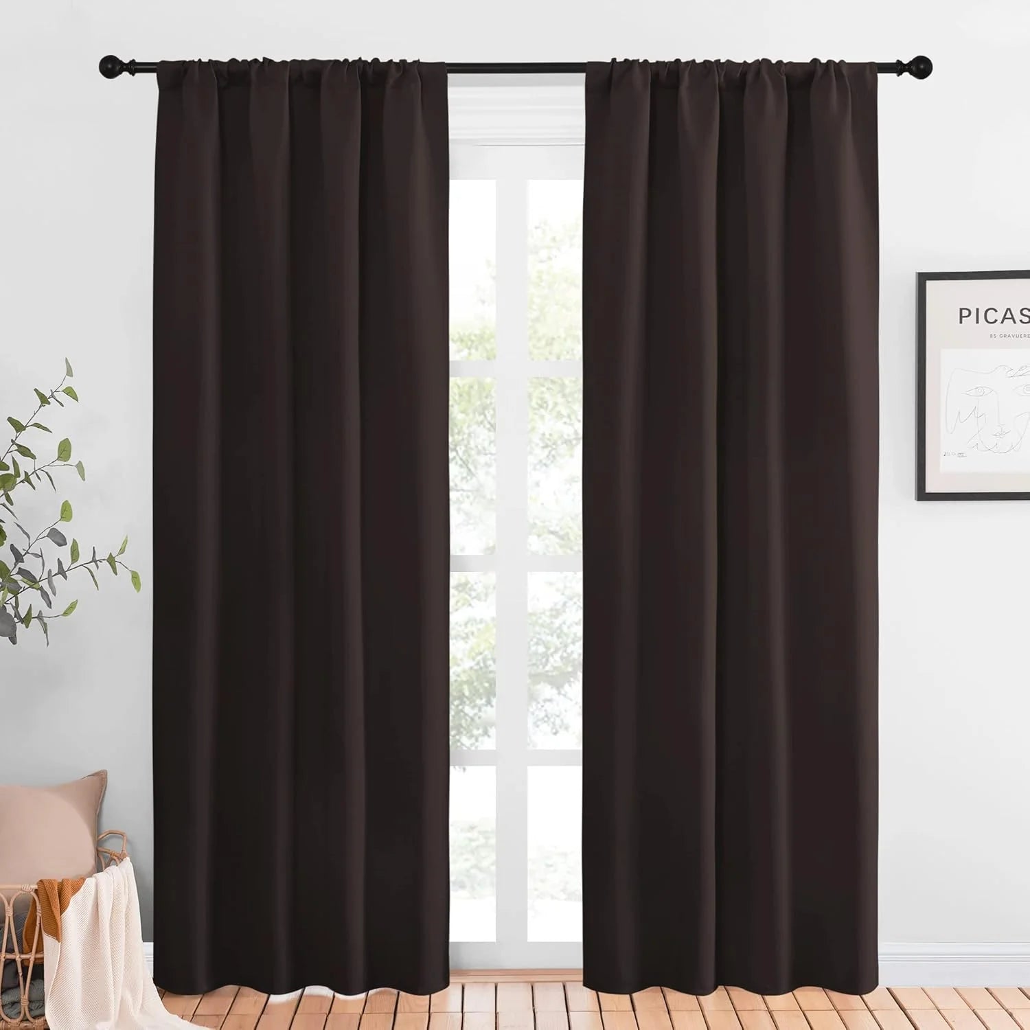 Dark brown blackout curtains hanging on a black rod in a bright modern room