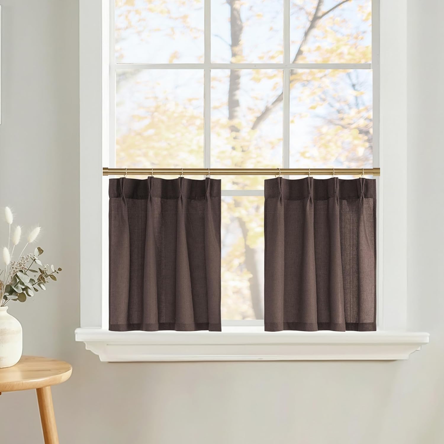 Dark brown linen-blend cafe curtains with pleated tops on a brass rod, covering the lower half of a window.