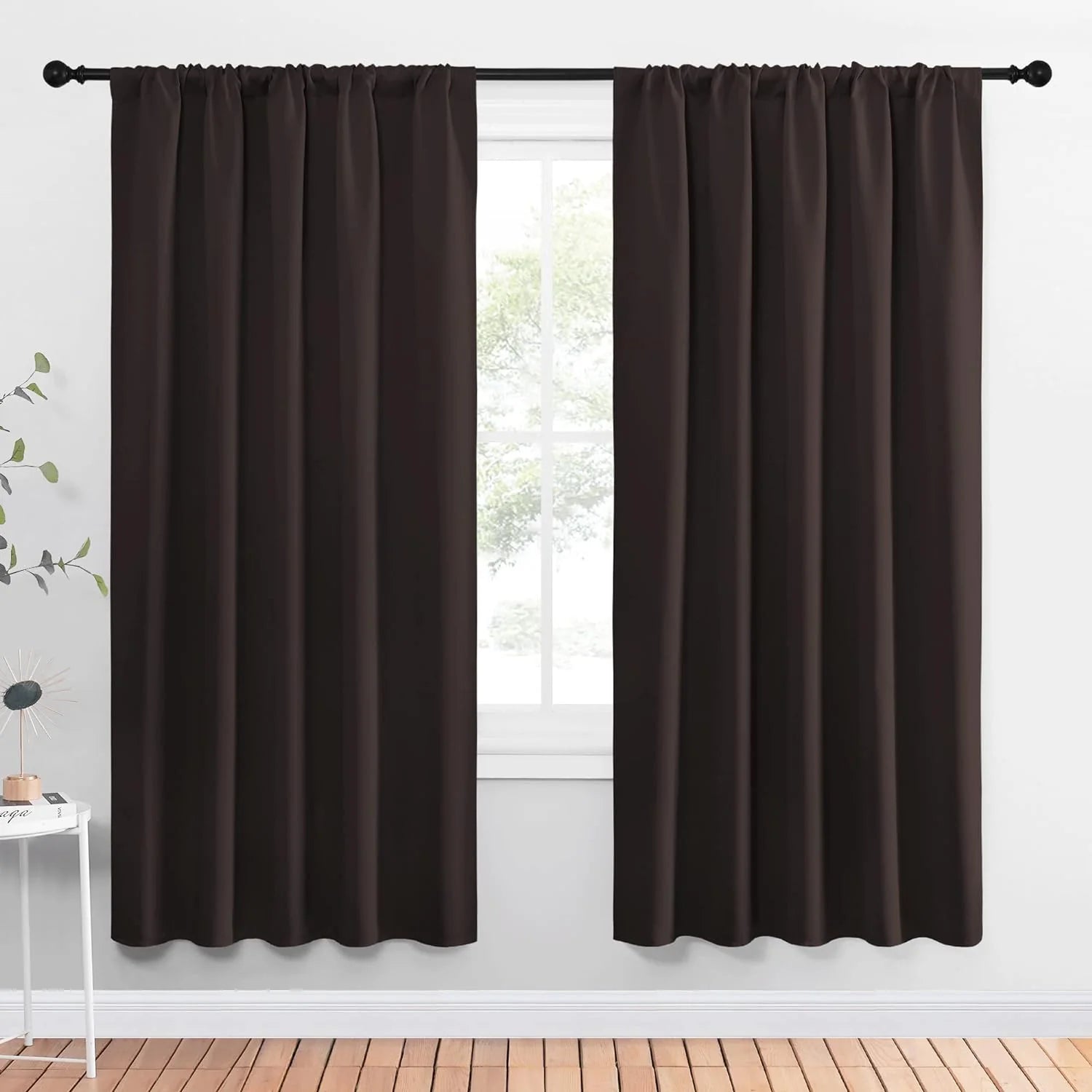 Dark brown rod pocket curtains hanging on a black curtain rod over a window
