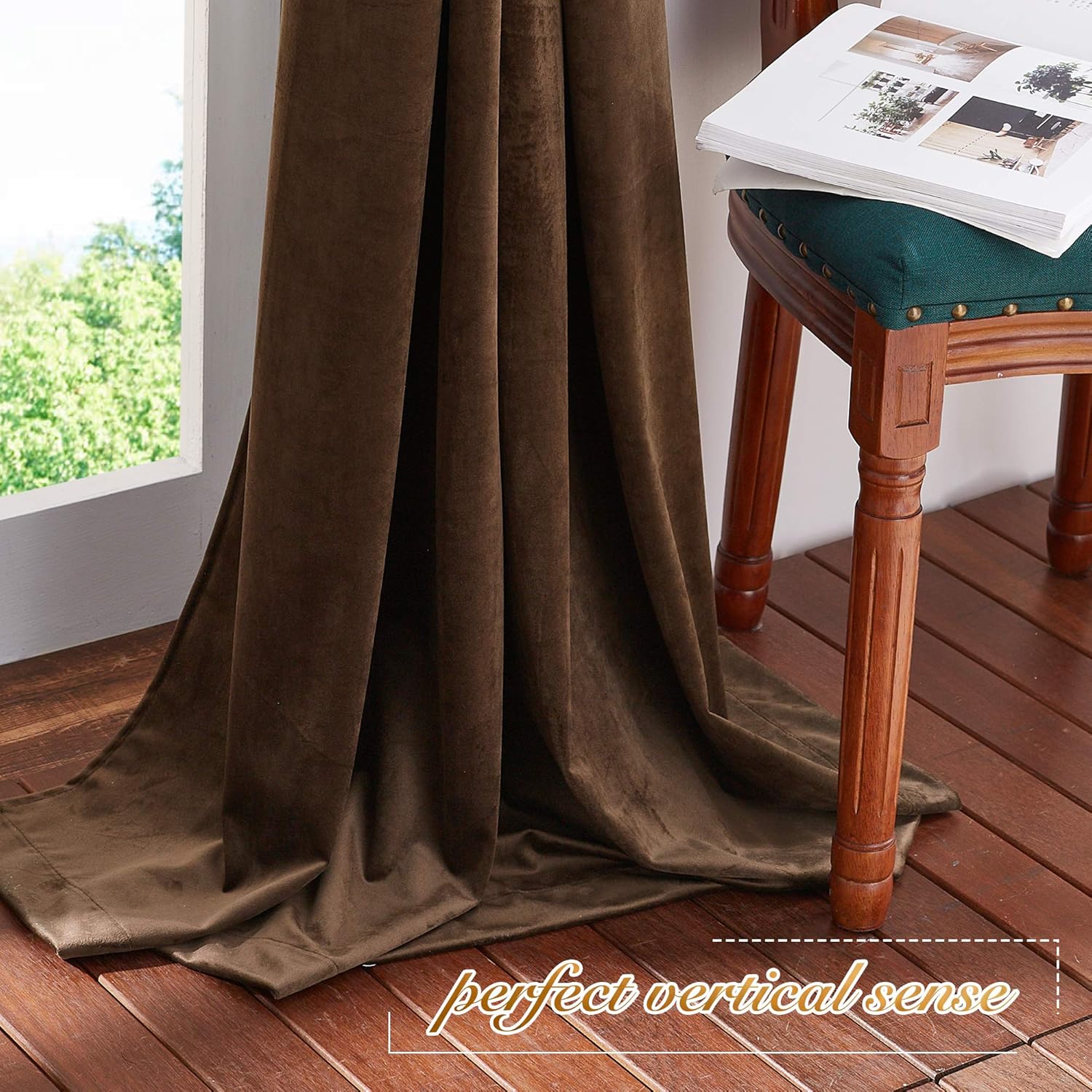 Dark brown velvet curtain panel hanging gracefully, pooling on wooden floor next to window.