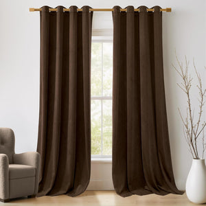 Two dark brown velvet grommet top curtains hanging on a gold rod over a window. The plush fabric drapes elegantly.