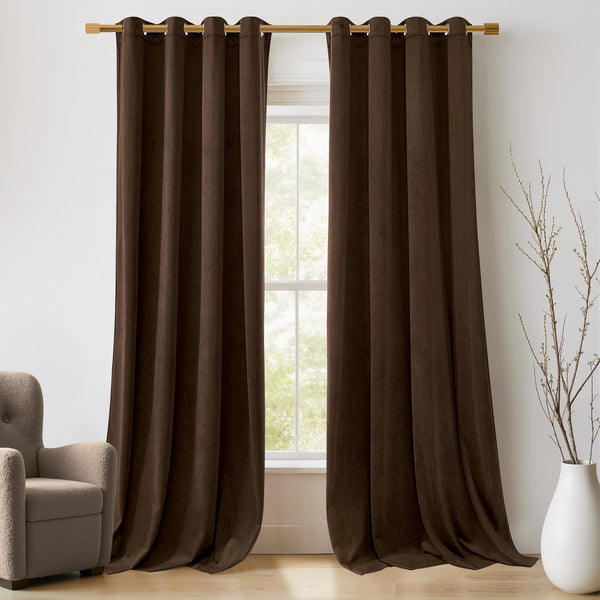 Two dark brown velvet grommet top curtains hanging on a gold rod over a window. The plush fabric drapes elegantly.