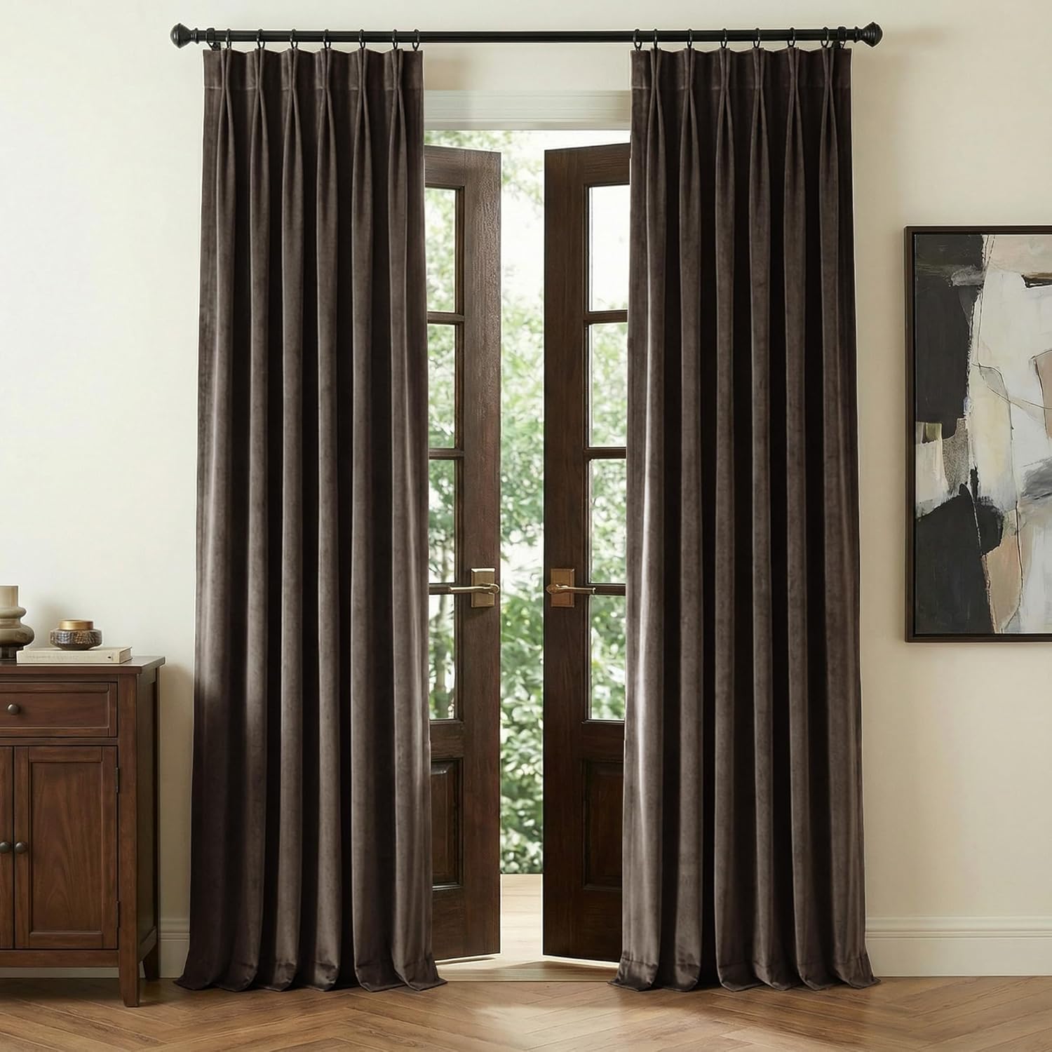 Dark brown velvet pinch pleat curtains hanging on a black rod, covering open French doors.