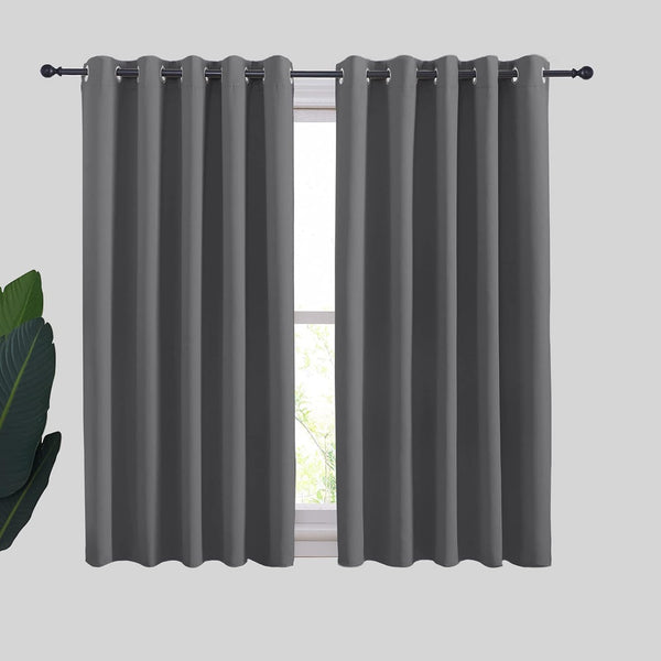 Two dark gray blackout curtain panels with silver grommet tops hang on a black rod above a window.