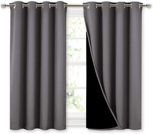 Dark gray blackout curtains with grommet tops hanging on a rod over a window.