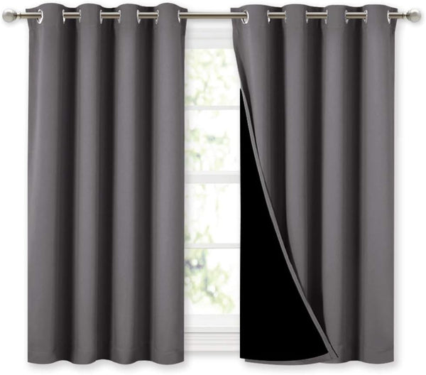 Dark gray blackout curtains with grommet tops hanging on a rod over a window.