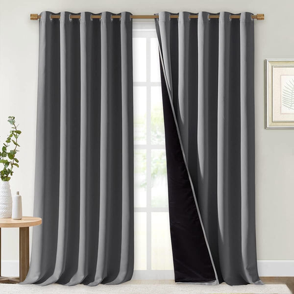 Dark gray blackout grommet curtains hung on a gold rod. One panel reveals black thermal lining.