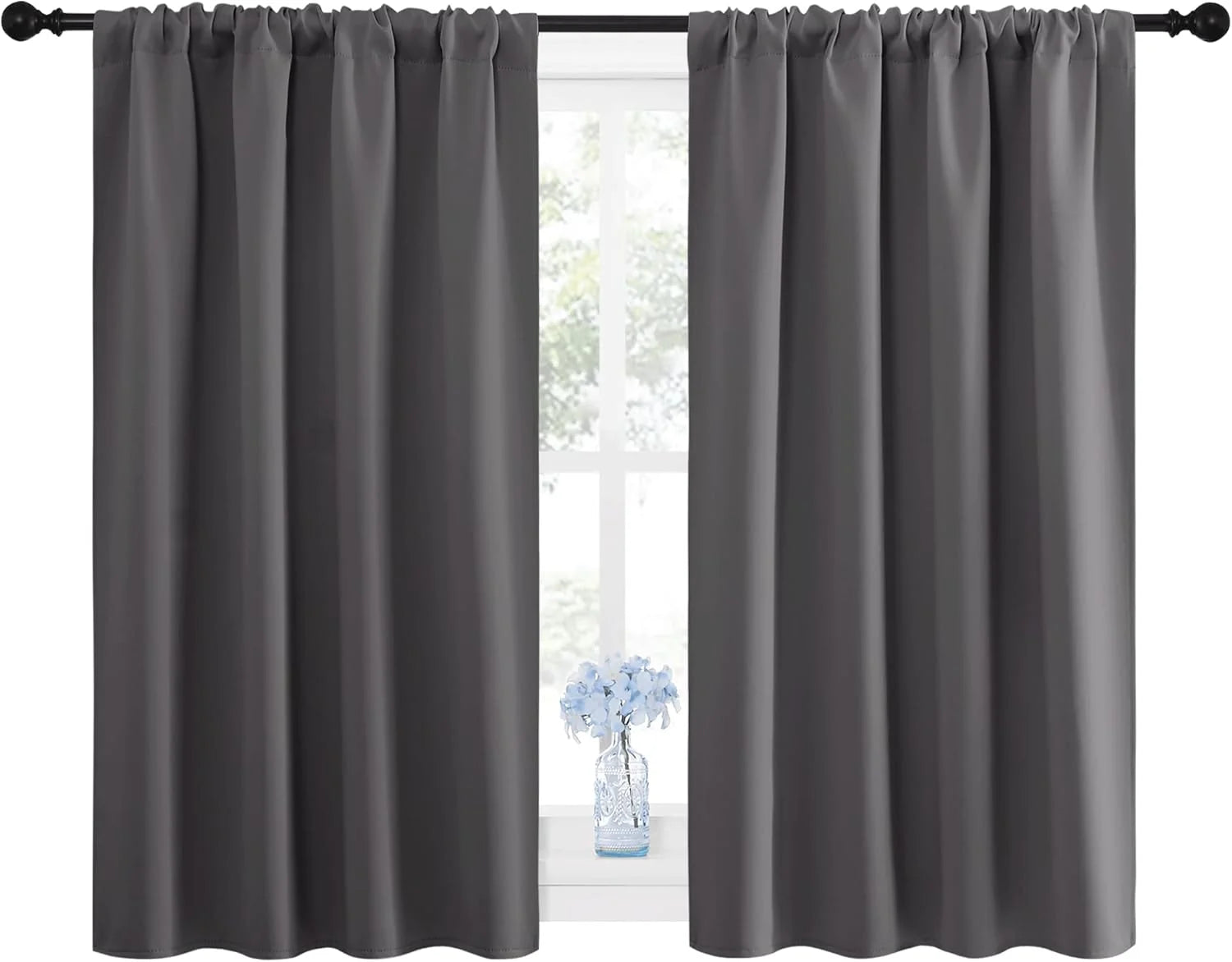 Pair of dark gray blackout curtains with rod pocket top hanging on a window
