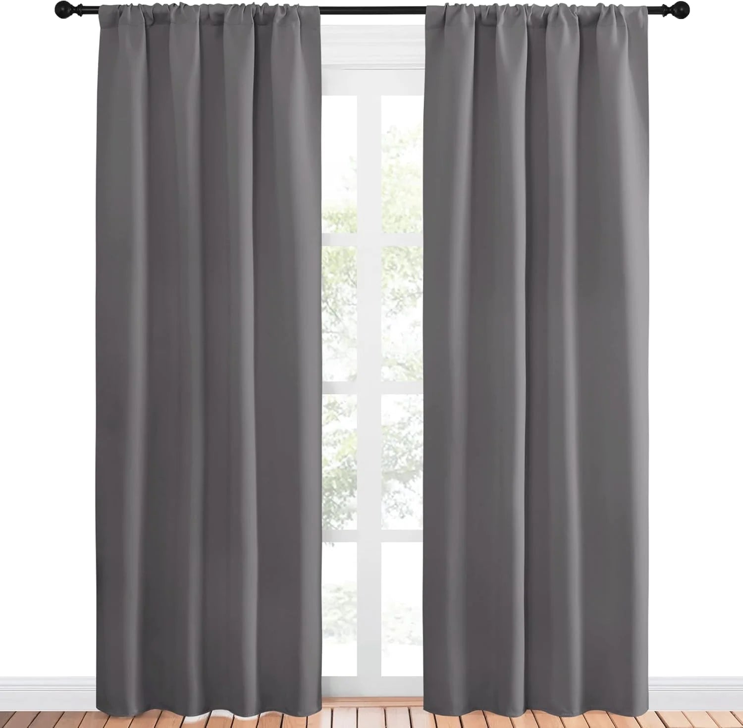 Dark gray rod pocket blackout curtains on a black rod in front of a window.