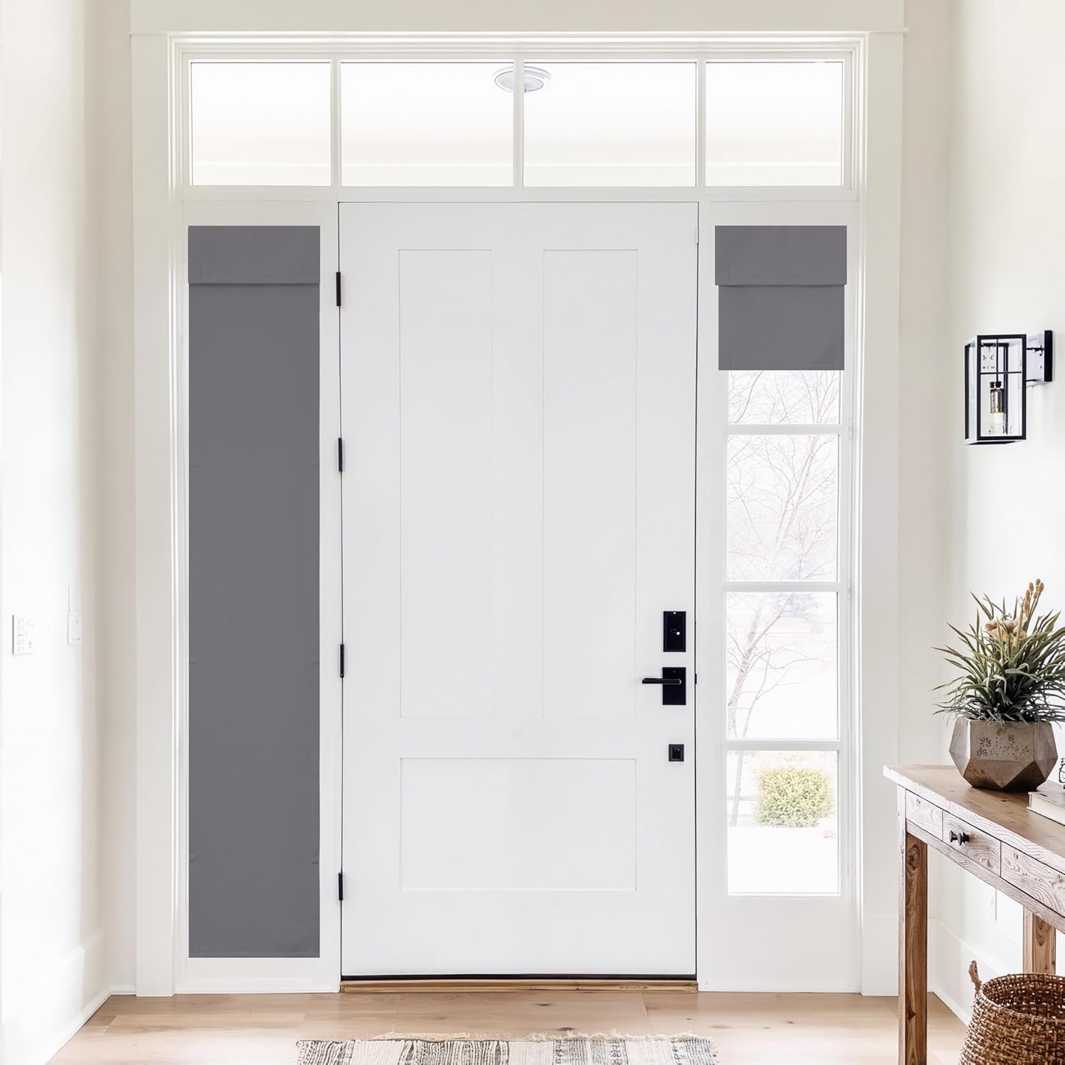 Modern dark gray fabric shades covering sidelight windows and transom above a white entry door.