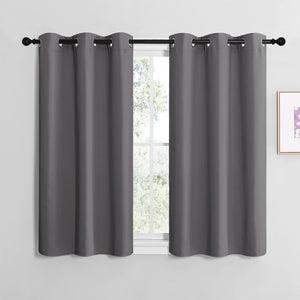 Pair of dark gray blackout curtain panels with silver grommets hanging on a black rod.