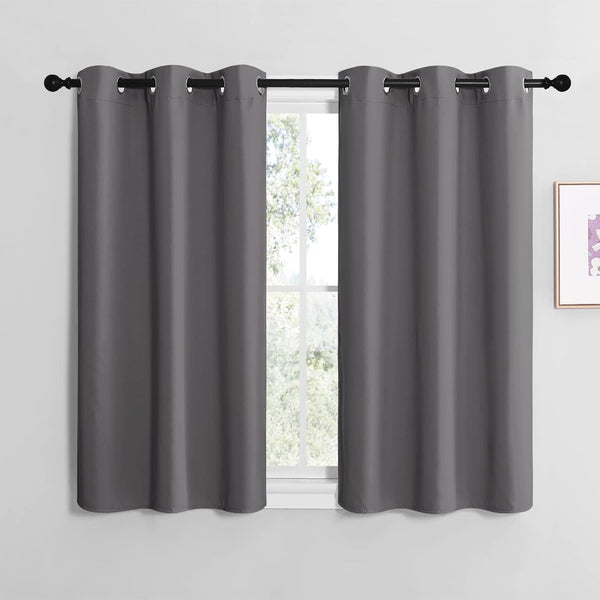 Pair of dark gray blackout curtain panels with silver grommets hanging on a black rod.