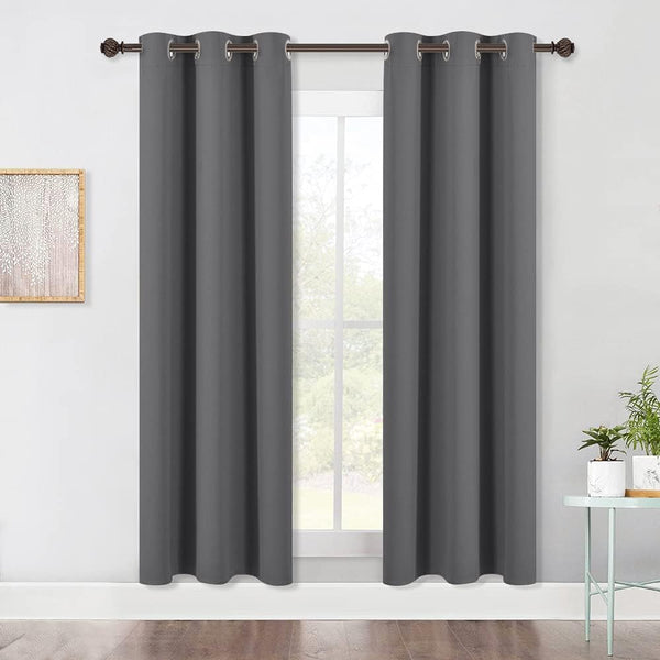 Two dark gray blackout curtains with silver grommet tops hanging on a bronze rod over a window.