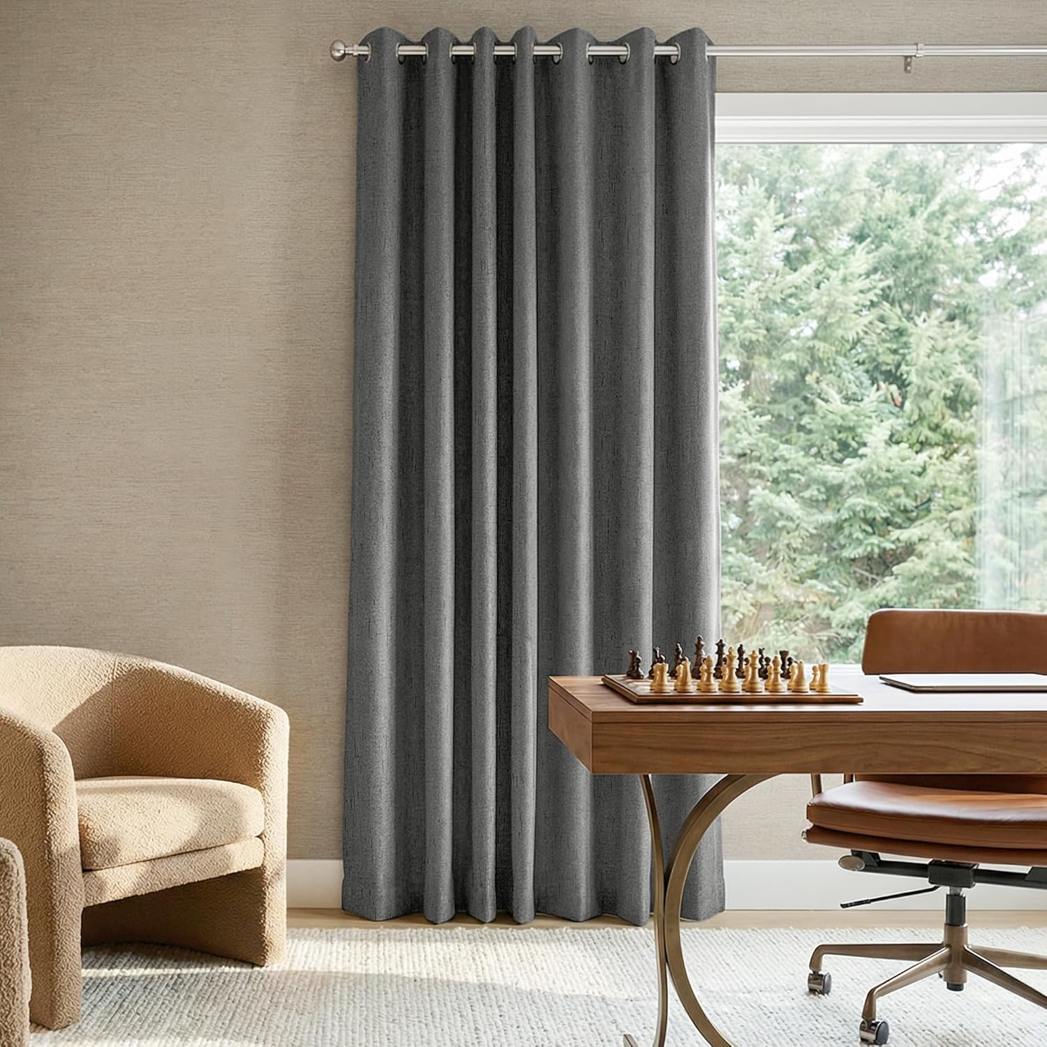 Dark gray textured grommet curtain panel on a silver rod, offering room darkening in a modern room.