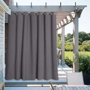 Dark gray weatherproof outdoor grommet curtain hanging from a wooden pergola on a sunny patio.