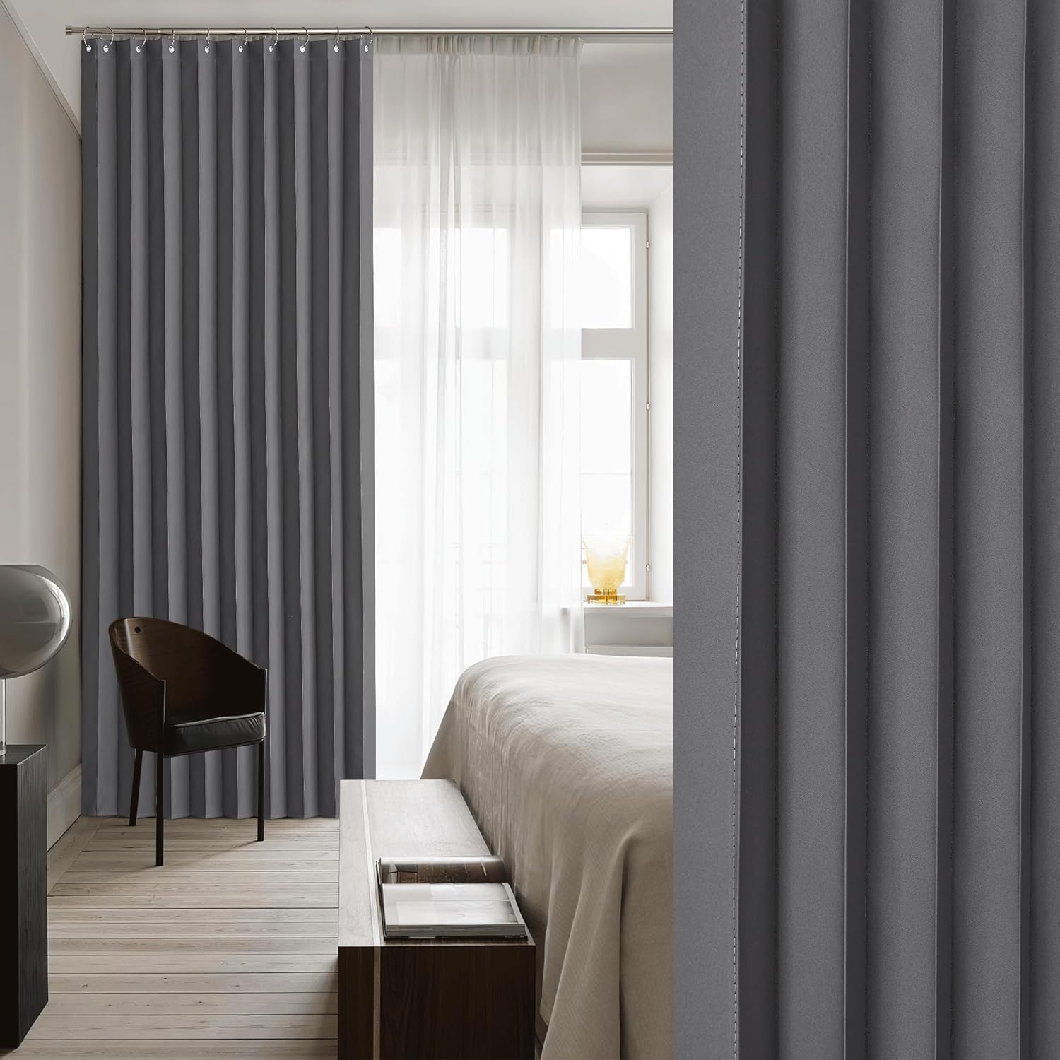 Dark gray pleated blackout curtains with subtle vertical stitching, hung on a rod in a modern bedroom.