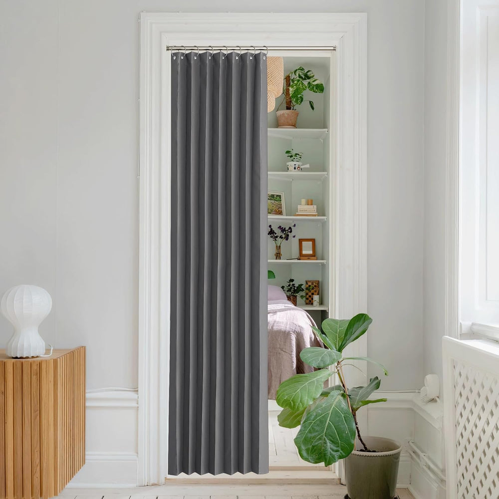 Dark gray pleated single panel curtain with grommet top, hanging in a white doorway as a modern room divider.
