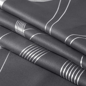 Close-up of folded dark gray fabric with shimmering silver abstract pattern of parallel stripes and curved lines