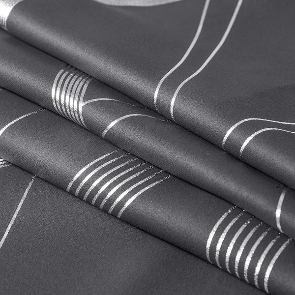 Close-up of folded dark gray fabric with shimmering silver abstract pattern of parallel stripes and curved lines
