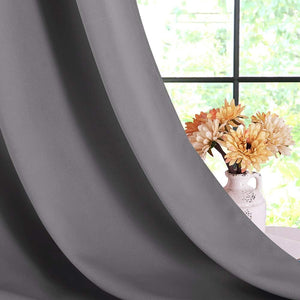 Close-up of a dark gray textured blackout curtain panel, elegantly draped by a window.