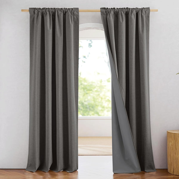 Dark gray textured rod pocket curtains, one panel slightly open revealing a gray lining, hanging over an arched window.
