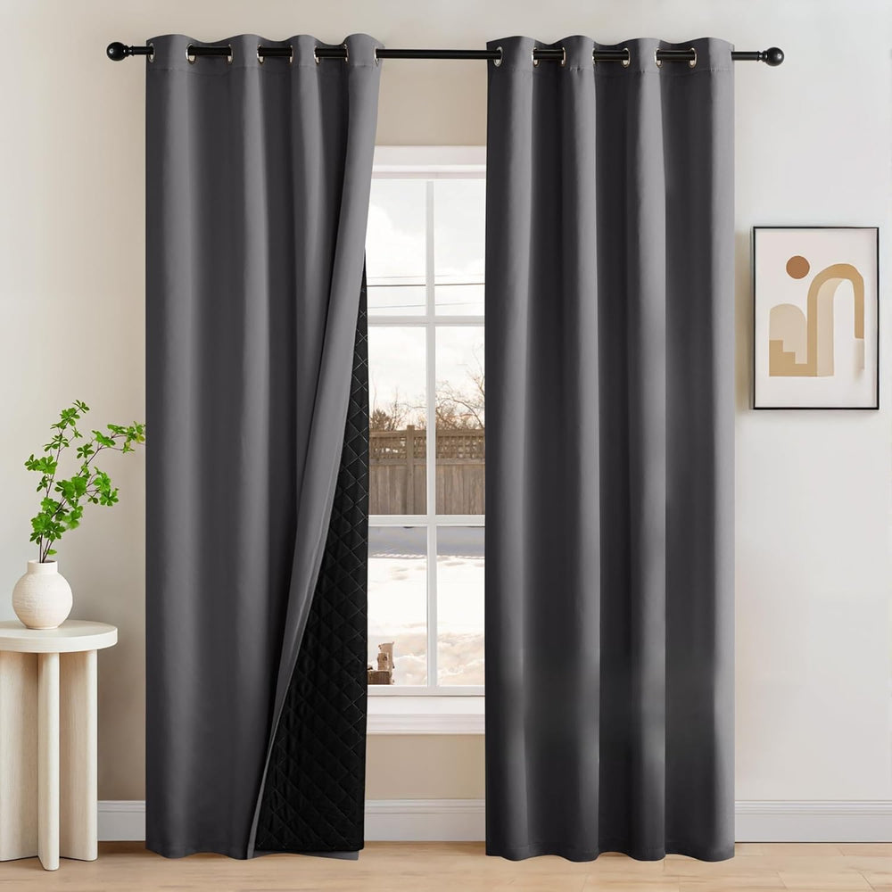 Pair of dark gray blackout curtains with silver grommets, revealing a thick quilted thermal lining.