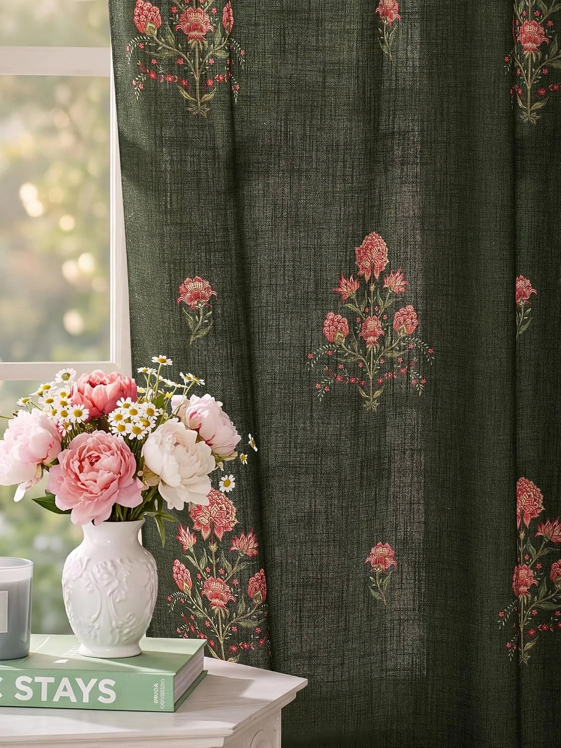 Dark green textured curtain with pink floral print beside a vase of fresh flowers