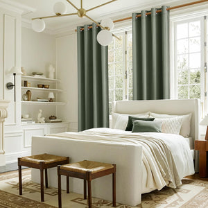 Dark green grommet curtains with metal rings framing large windows in a bright, modern bedroom.