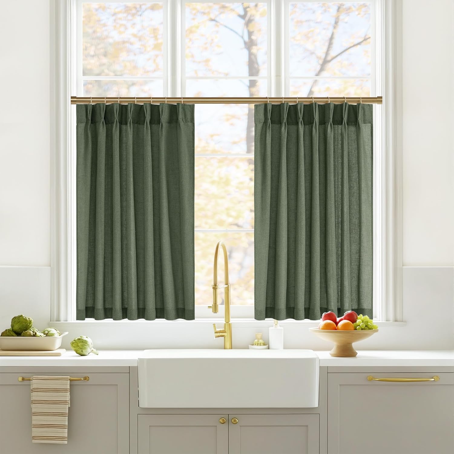 Two dark green linen blend cafe curtains with rod pockets on a brass rod over a kitchen sink.