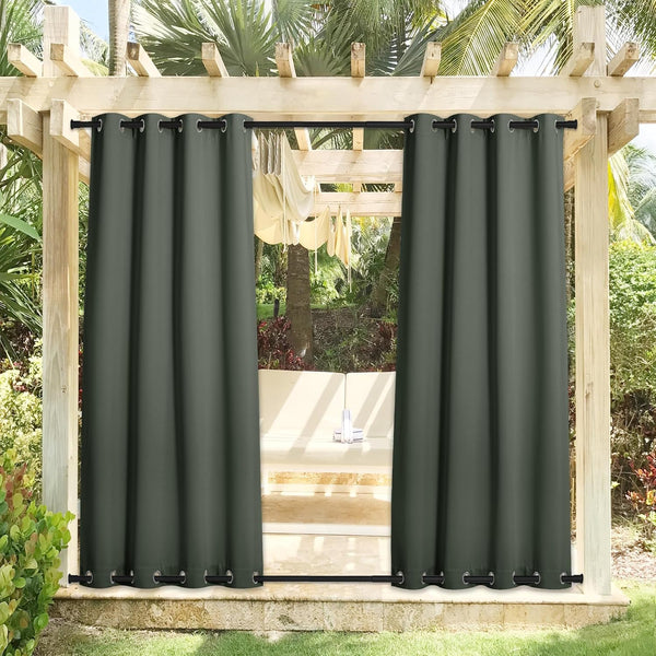 Two dark green outdoor grommet curtains hang on a wooden pergola, providing patio shade and privacy.