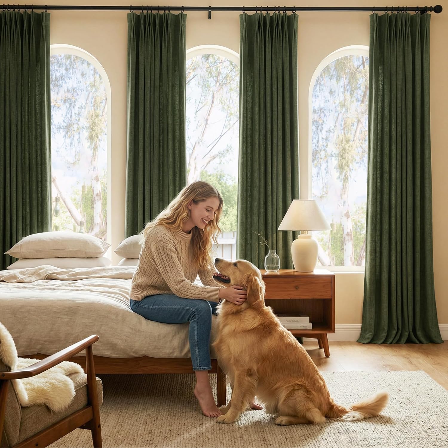 Dark green textured pinch pleat curtains hang on arched windows in a cozy, sunlit bedroom.
