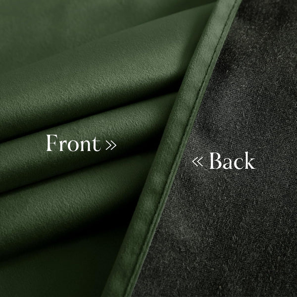 Close-up of dark green velvet curtain fabric showing the soft front and textured black blackout lining on the back.