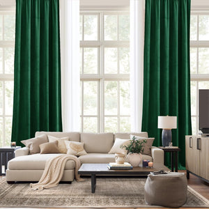 Dark green velvet curtain panels with gathered tops framing large windows in a bright, modern living room.