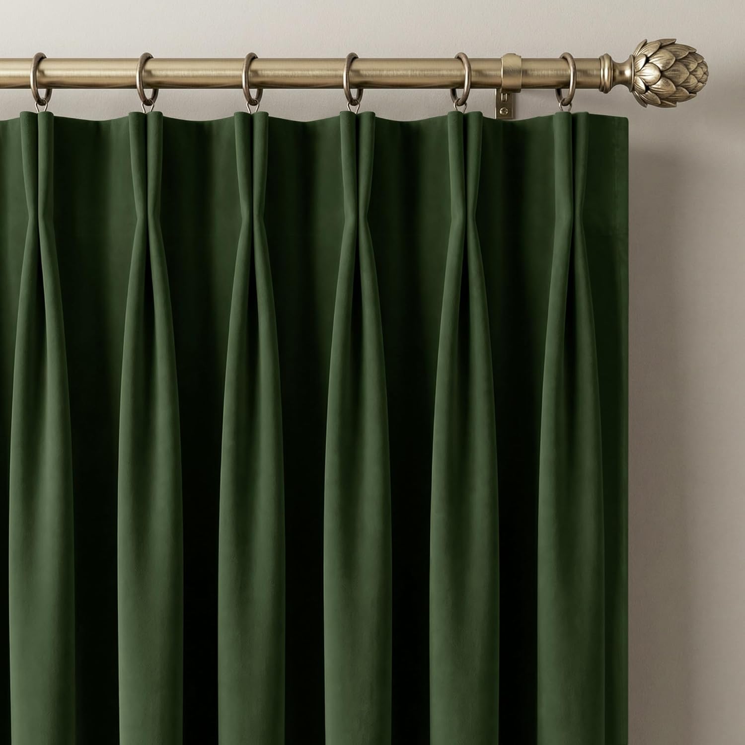 Rich dark green velvet pinch pleat curtain on a decorative brass rod.