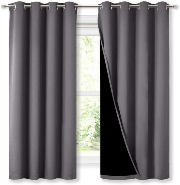 Dark grey blackout curtains with grommet top hanging on a rod. Right panel shows its black thermal lining.