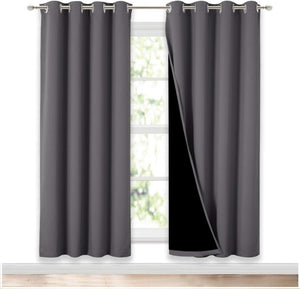Dark grey blackout curtains with silver grommet tops, showing black lining, hanging over a window.
